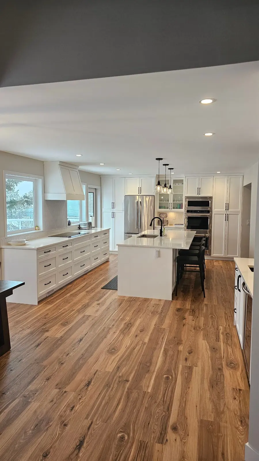 Bright finished kitchen with recessed ceiling lighting and pendant lights over the island.